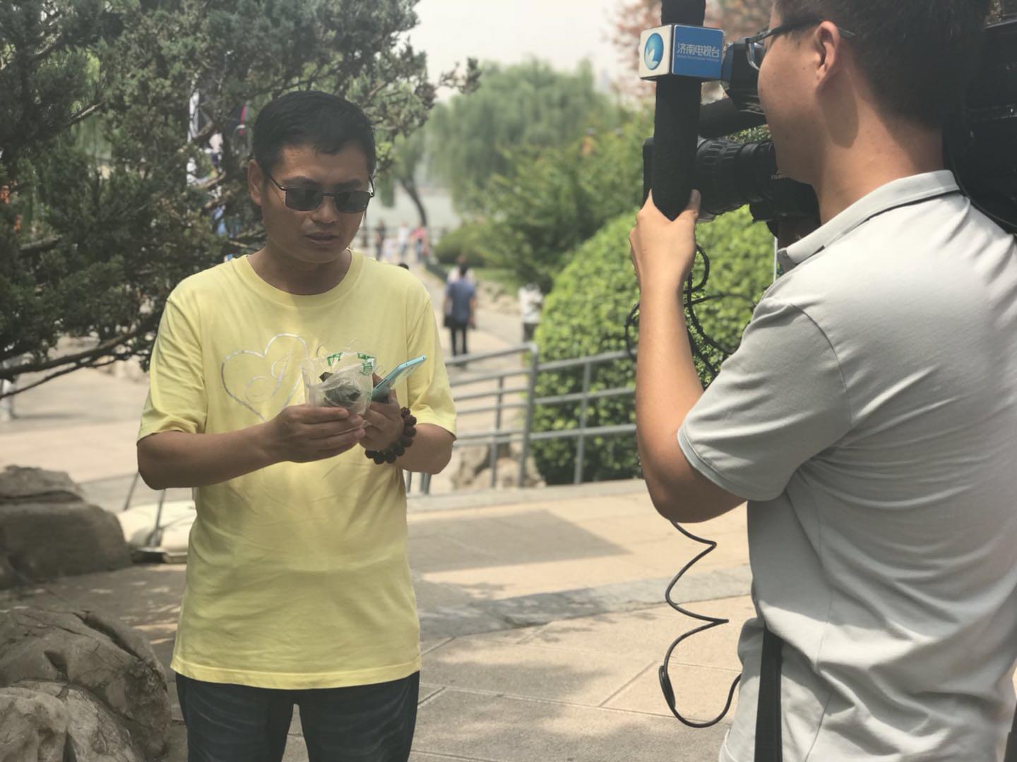 领到荷叶粽的市民心情激动地接受电视台采访