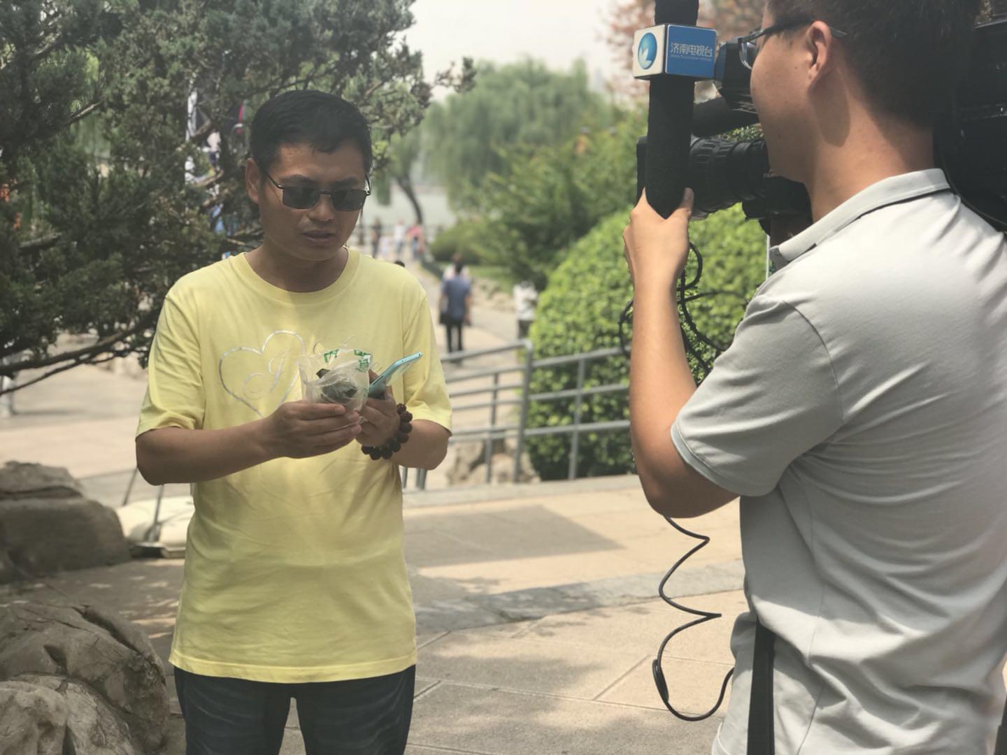 领到荷叶粽的市民心情激动地接受电视台采访